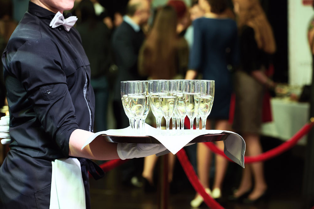 catering or celebration concept. Waiter holding a tray with glasses of vine at party