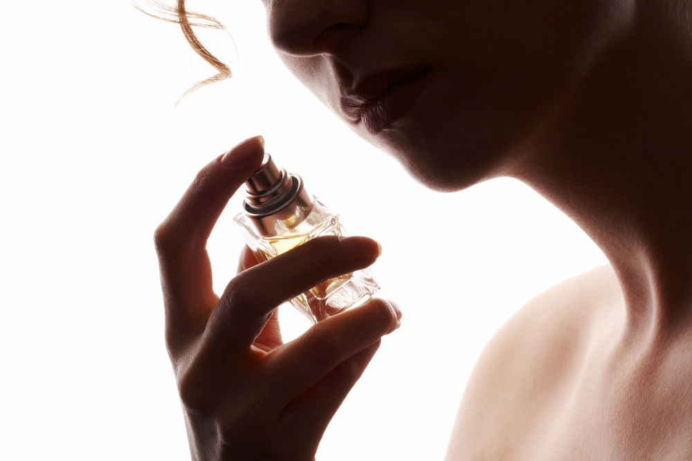 sensual woman smelling perfume, golden perfume bottle