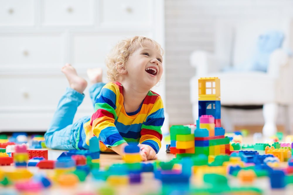 Child playing with colorful toy blocks. Little boy building tower at home or day care