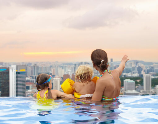 Family swimming in roof top outdoor pool on family vacation in Singapore