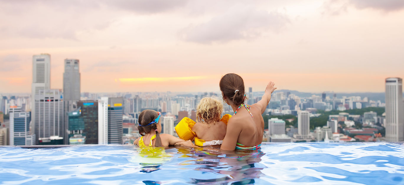 Family swimming in roof top outdoor pool on family vacation in Singapore