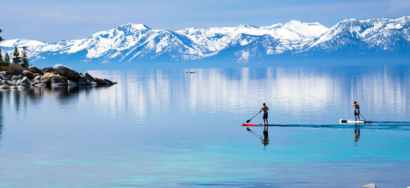 wo guys paddle boarding calm waters, Lake Tahoe