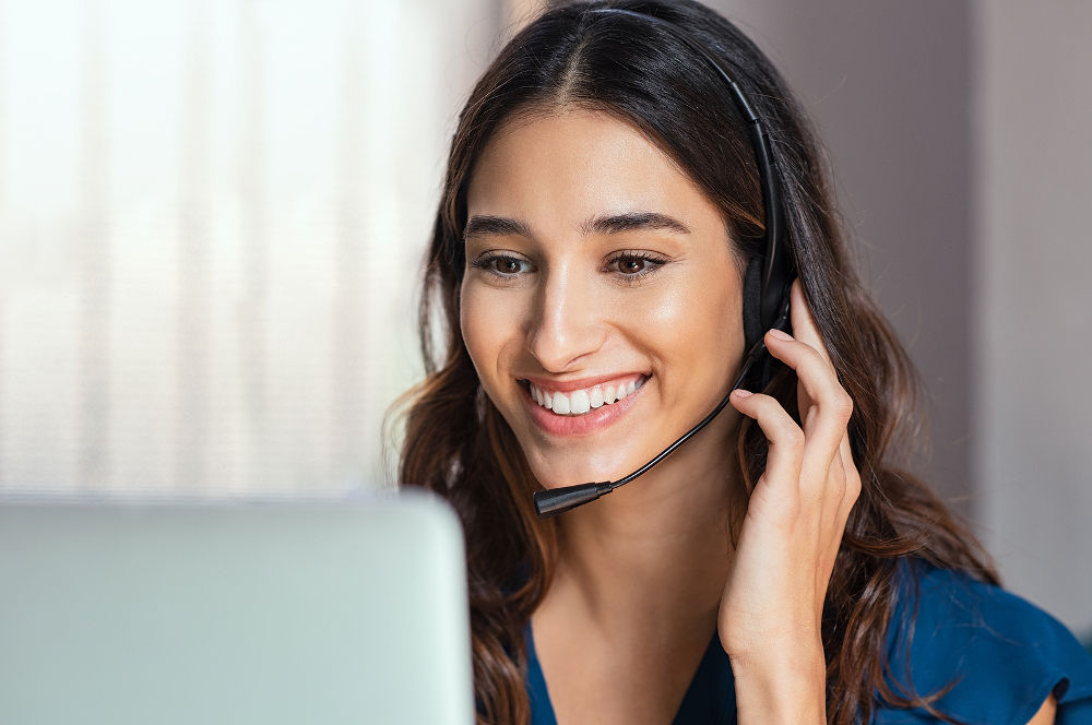 Smiling woman using laptop while talking to customer on phone