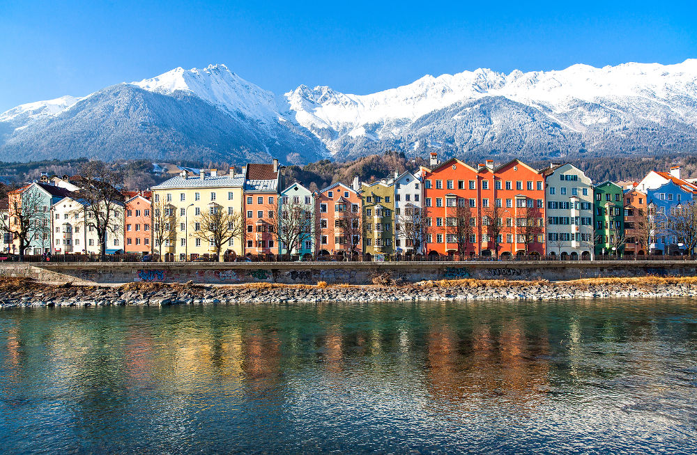 Austria Tyrol Innsbruck the Mariahilf strasse colored houses on the Inn river with the snowy mountains in the background