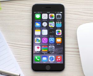 New phone iPhone 6 Space Gray with apps on screen lies on the table. iPhone 6 was created and developed by the Apple inc.